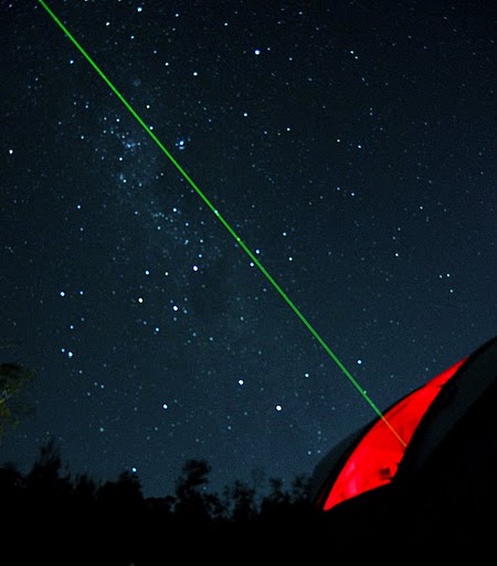 green laser pointer pointing at the sky