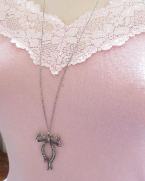 Antique silver tone bow pendant decorated with marcasite stones on a long, thin chain