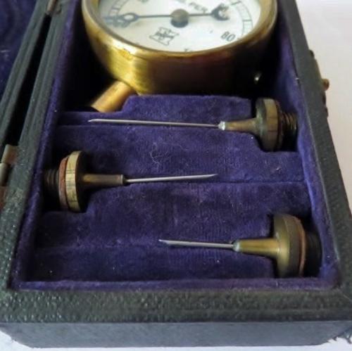 Small antique cast iron pressure gauge with brass plated trim in original case with 3 needles