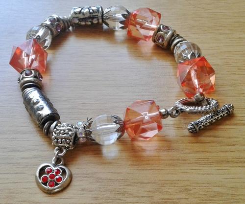 Fashion bracelet with metallic, clear and peach beads with heart shaped charm