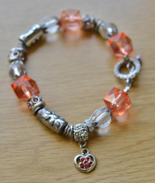 Fashion bracelet with metallic, clear and peach beads with heart shaped charm